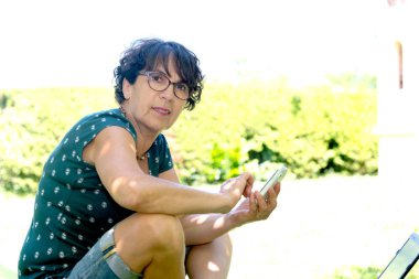 smartphone kullanarak Bahçe güverte sandalyede oturan kadın