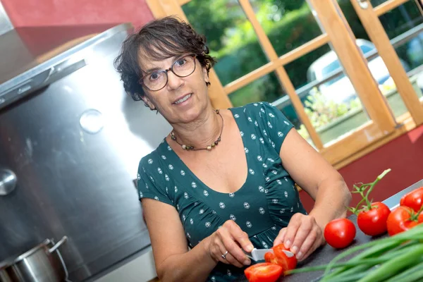 Mujer de mediana edad preparando la comida con tomates — Foto de Stock