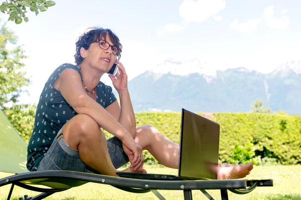 smartphone kullanarak Bahçe güverte sandalyede oturan kadın