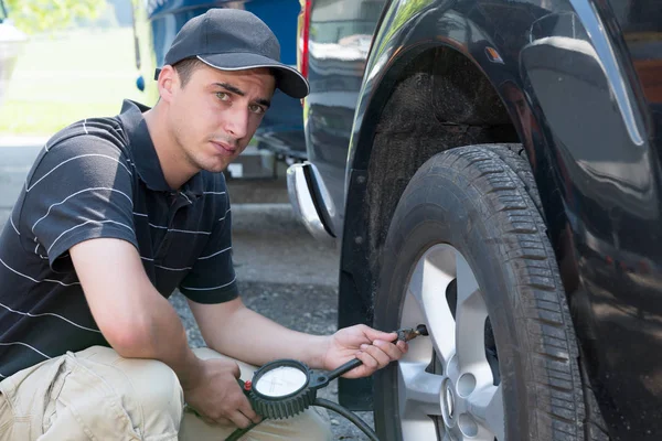 Hombre joven controla la presión del neumático — Foto de Stock
