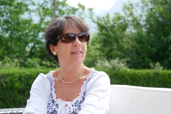 Retrato de una mujer sonriente de mediana edad sentada en el jardín en casa —  Fotos de Stock