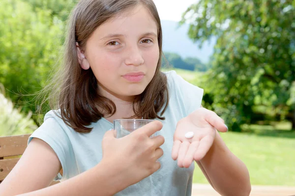 Schattig meisje kind nemen pil met glas water — Stockfoto