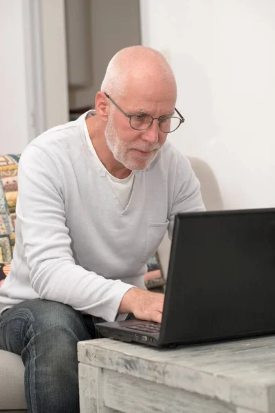 Homme âgé avec ordinateur portable assis dans le canapé — Photo