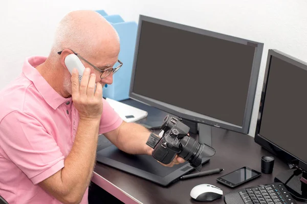 Fotograaf met de camera op kantoor met computer — Stockfoto