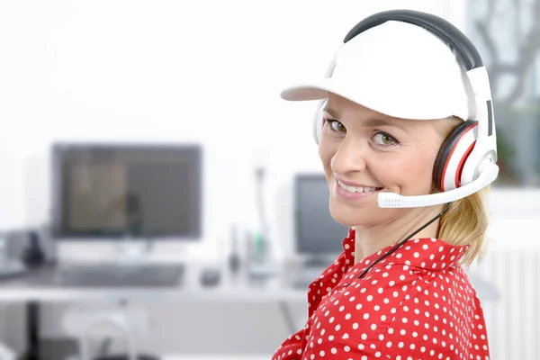 Blond młoda kobieta z zestawu słuchawkowego i white cap — Zdjęcie stockowe