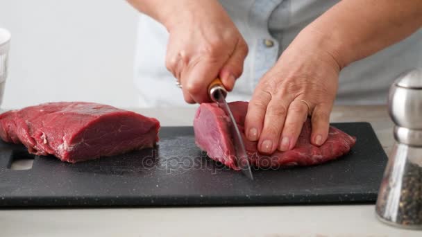 Cutting raw beef on a cutting board closeup — Stock Video