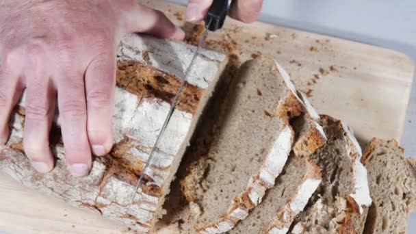 Мужские руки режут традиционный кусок хлеба — стоковое видео