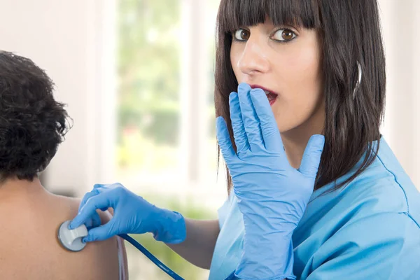 Femme médecin examine un patient avec un stéthoscope — Photo