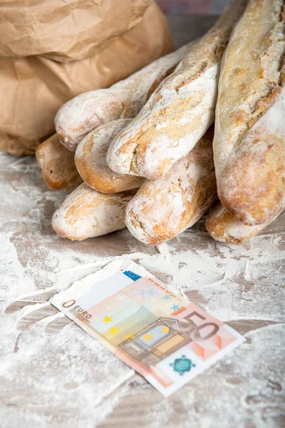 French bread with money on a rustic table — Stock Photo, Image