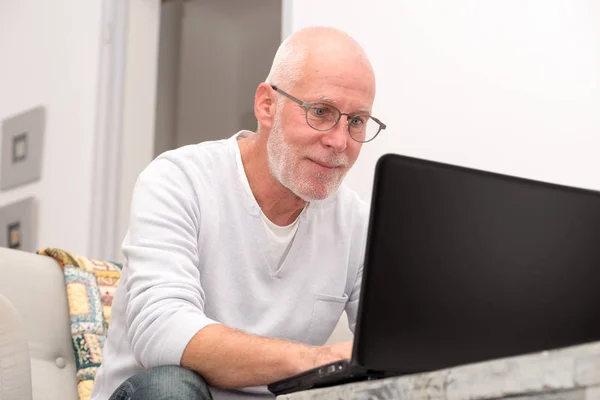 Homme âgé avec ordinateur portable assis dans le canapé — Photo