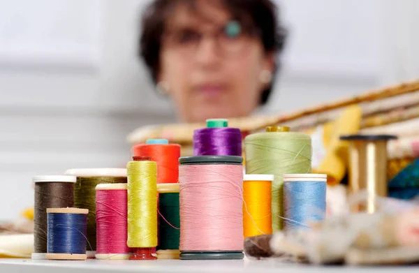 Carretes de hilos de colores, costurera en la parte inferior — Foto de Stock