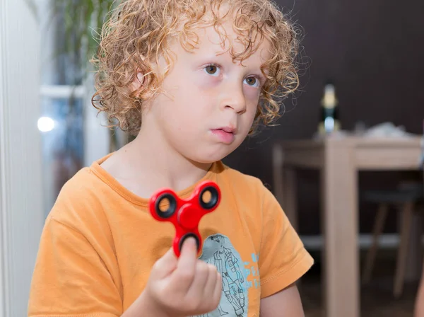 Liten blond pojke leker med hand spinner — Stockfoto