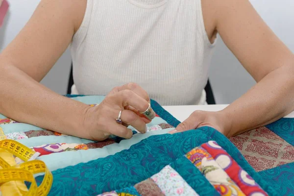 Frauenhände nähen für die Fertigstellung einer Decke. — Stockfoto