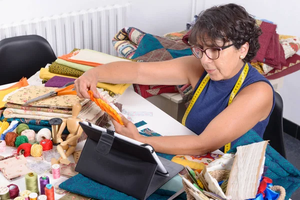 Mooie rijpe naaister met behulp van tablet pc — Stockfoto