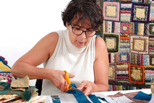 Зрелая брюнетка женщина режет ткань для шитья лоскутной работы — стоковое фото