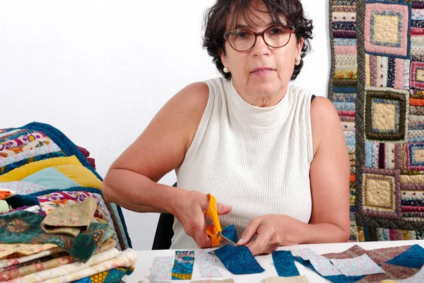 Зрелая брюнетка женщина режет ткань для шитья лоскутной работы — стоковое фото