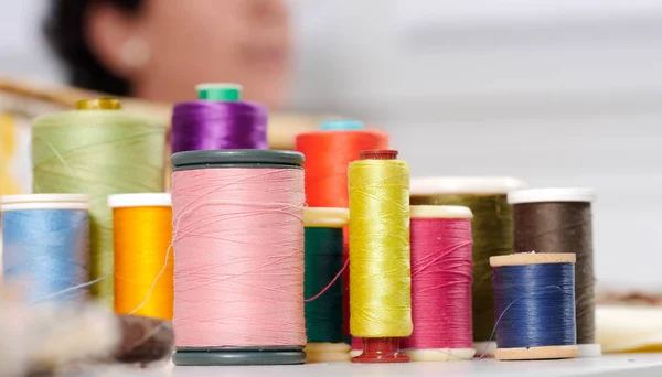 Rollen van gekleurde draden, naaister onderaan — Stockfoto