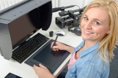 Tablet kullanarak bilgisayarda çalışan genç grafik tasarımcı