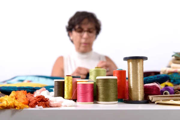 Rollen van gekleurde draden, naaister onderaan — Stockfoto