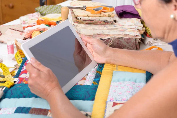 Mooie rijpe naaister met behulp van tablet pc — Stockfoto