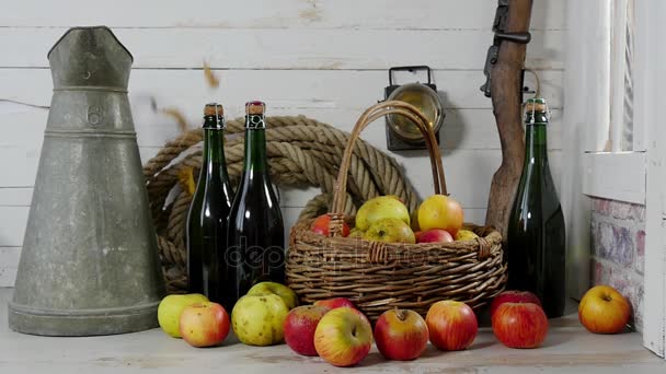 Осень, желтые листья падают на яблоки и бутылку сидра — стоковое видео