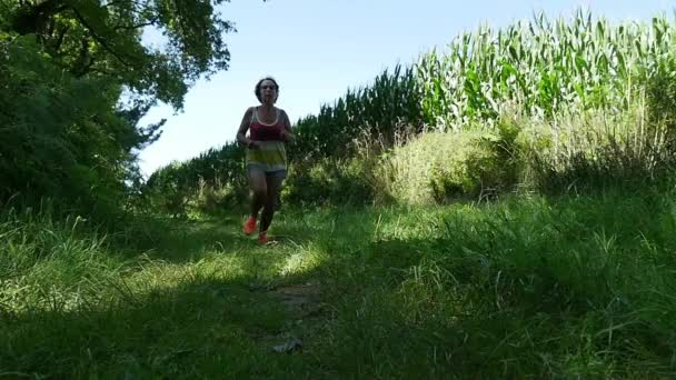 Uma mulher correndo em um caminho no campo, câmera lenta — Vídeo de Stock