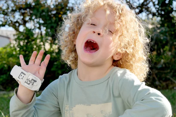 Niño pequeño con el pelo rubio y rizado haciendo caras —  Fotos de Stock