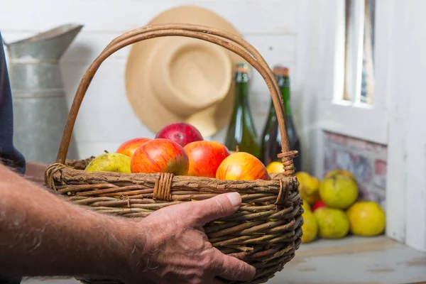 Hombre sosteniendo una cesta llena de manzanas — Foto de Stock