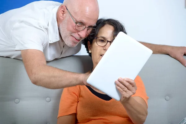 Senior couple using a tablet and smiling — Stock Photo, Image