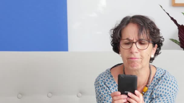 Una mujer mayor usando un teléfono inteligente y sonriendo — Vídeo de stock