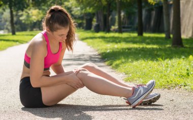 genç kadın atlet açık havada ağrı dizime dokunma