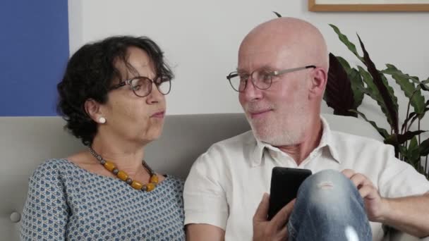 Senior paar met behulp van een smartphone en glimlachen — Stockvideo