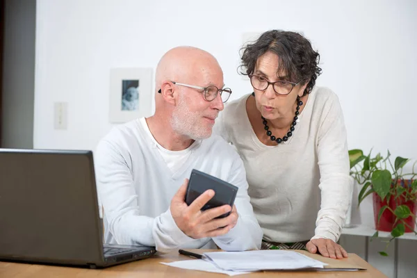 Senior couple paying their bills with laptop at home — Stock Photo, Image