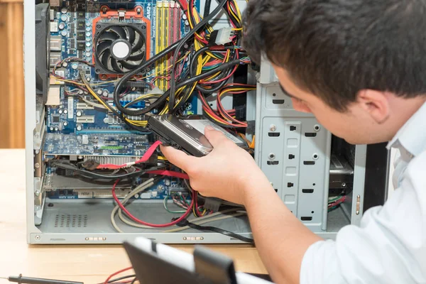 Technik pracující na rozbité počítače ve své kanceláři — Stock fotografie