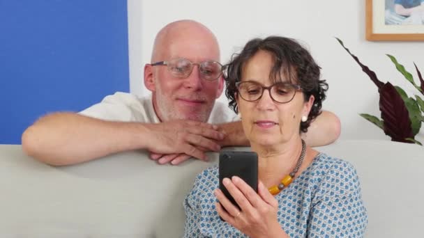 Couple sénior utilisant un smartphone et souriant — Video