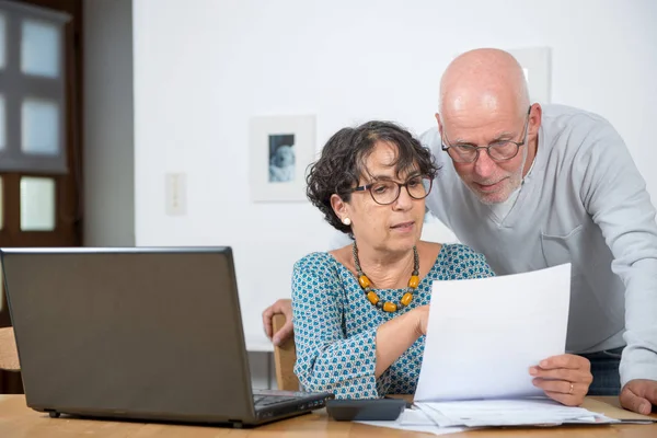 Senior couple paying their bills with laptop at home — Stock Photo, Image