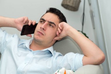 genç adam ciddi bir ifade ile cep telefonuna arıyor