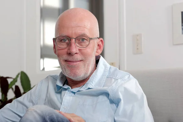 Älterer Mann mit Glatze und Brille sitzt auf Sofa — Stockfoto