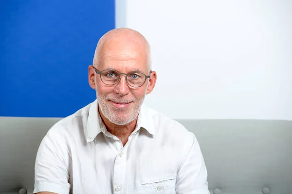 Älterer Mann mit Glatze und Brille sitzt auf Sofa — Stockfoto