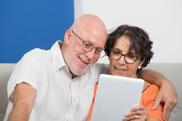 Mature couple using a tablet and smiling — Stock Photo, Image
