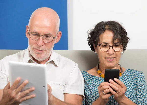 Mature couple using smartphone and tablet — Stock Photo, Image