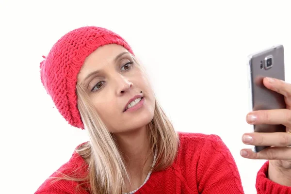 Красива молода блондинка з червоною шапочкою за допомогою телефону — стокове фото