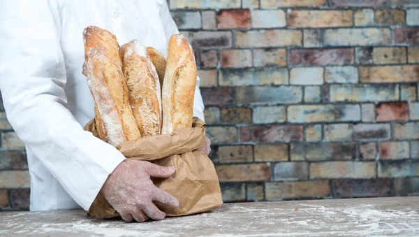Baker holding traditional bread french baguettes — Stock Photo, Image