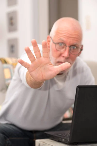 Θυμωμένος ανώτερος άνθρωπος χρησιμοποιώντας ένα φορητό υπολογιστή στο σπίτι — Φωτογραφία Αρχείου