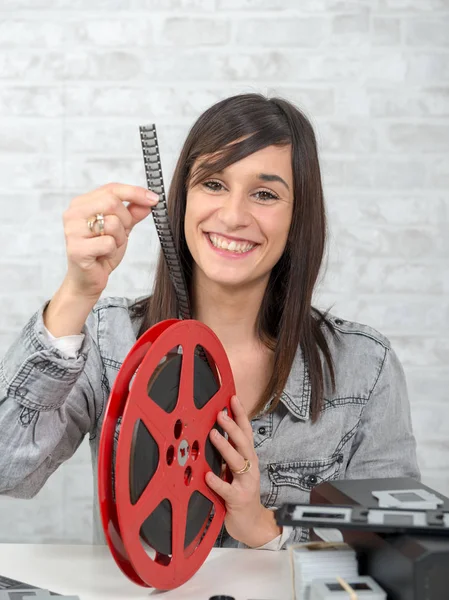 Pretty young woman looking at reel 16mm film — Stock Photo, Image