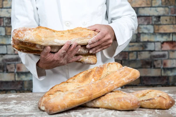 Baker holding traditional bread french baguettes — Stock Photo, Image
