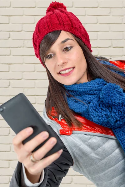 Молодая женщина в зимней кепке, используя смартфон — стоковое фото