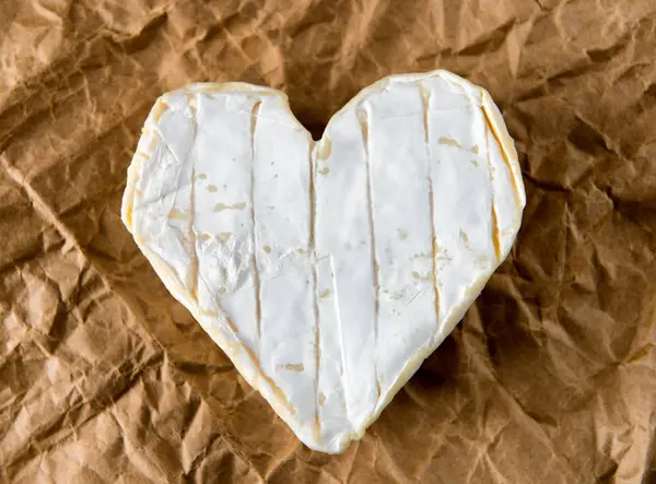 Queso francés Neufchatel en forma de corazón sobre papel —  Fotos de Stock