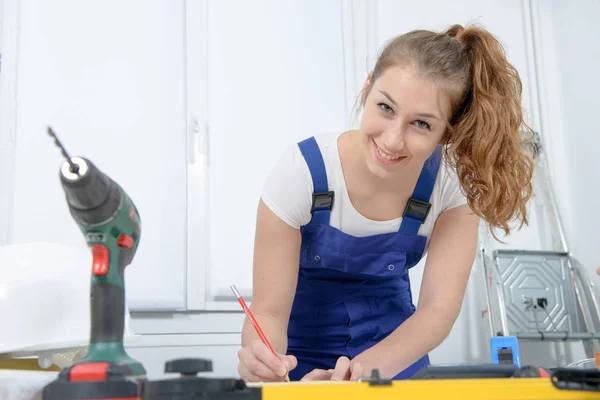 Graziosa ragazza costruttore misurare un asse di legno — Foto Stock