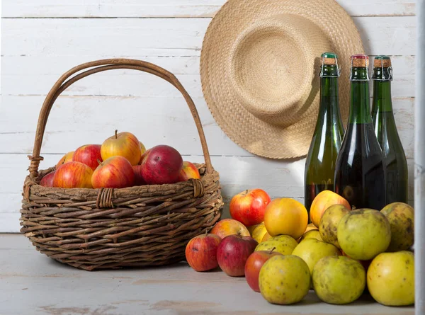 Tres botellas de sidra y cesta de manzanas — Foto de Stock
